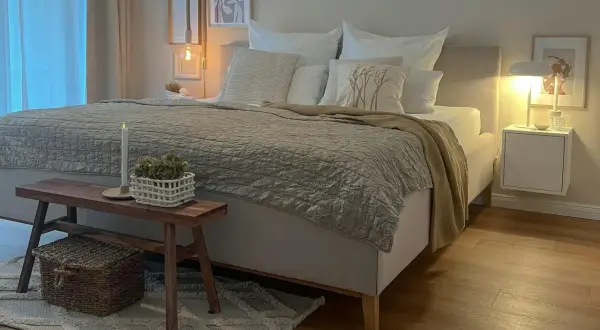Gemütliches Schlafzimmer in Beige: Bett mit Steppdecke, Kissen und Holzbank. Tolle schlafzimmer beige ideen für eine entspannte Atmosphäre.