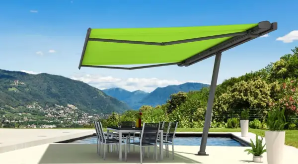 Moderne sonnensegel befestigen ideen: ein ausfahrbares Sonnensegel schützt eine Terrasse mit Esstisch und Stühlen vor der Sonne, mit Bergpanorama.