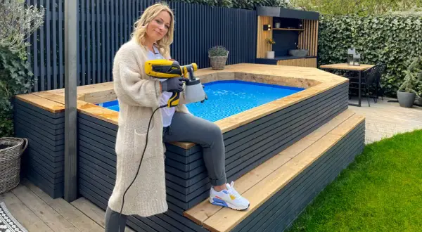 Frau mit Sprühgerät verkleidet aufstellpool mit Holz.