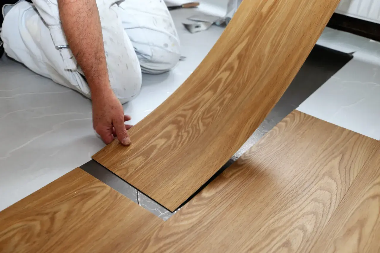 Hand verlegt Holzoptik-Vinylboden. Die Dielen werden präzise nebeneinander gelegt, um ein schönes Ergebnis zu erzielen.