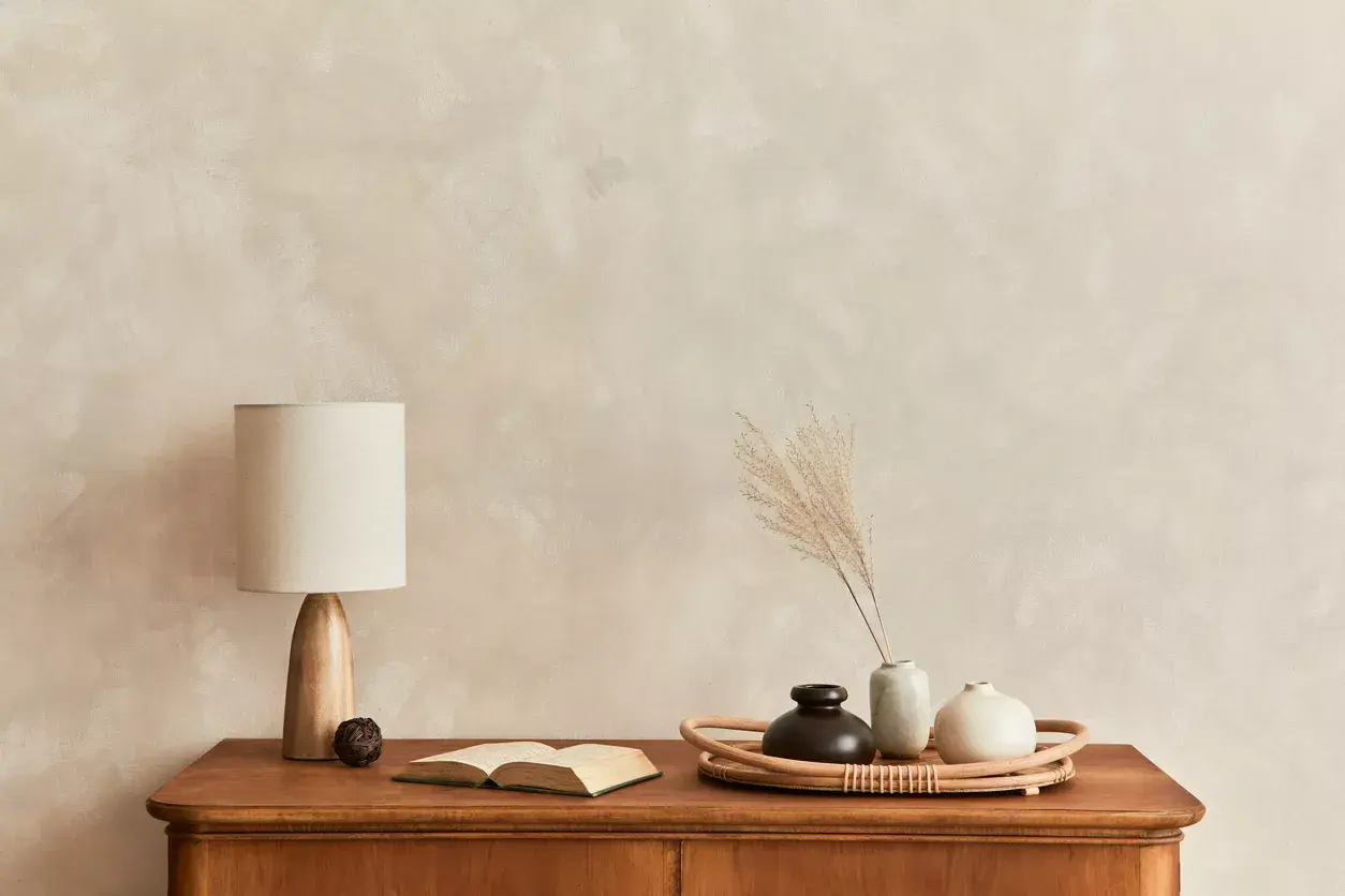 Eine Kommode mit Lampe, Buch und Vasen vor einer Wand mit **limewash technik**.