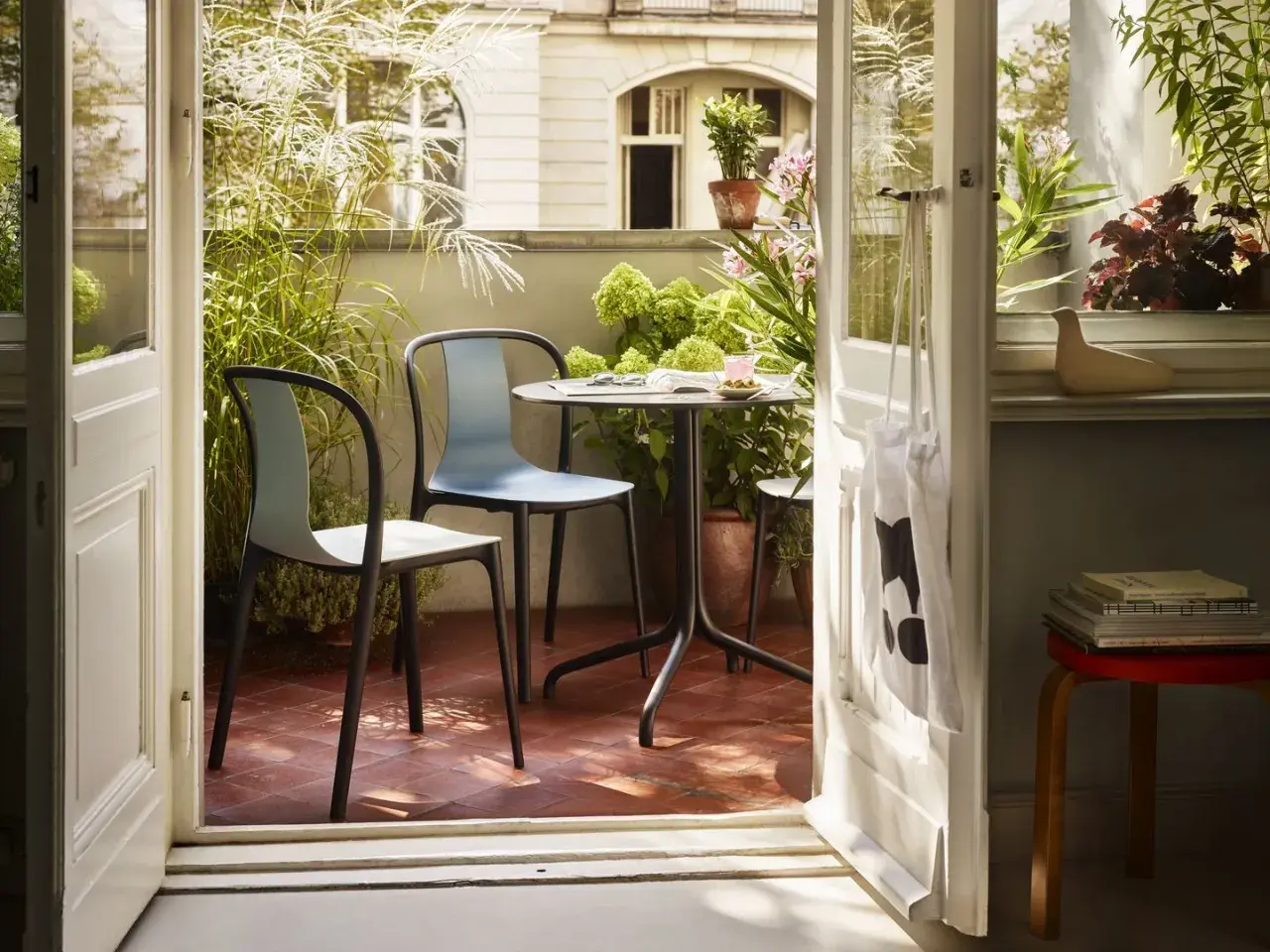 Gemütliche Balkon Ideen: Ein Tisch mit zwei Stühlen lädt zum Verweilen ein, umgeben von üppigem Grün.