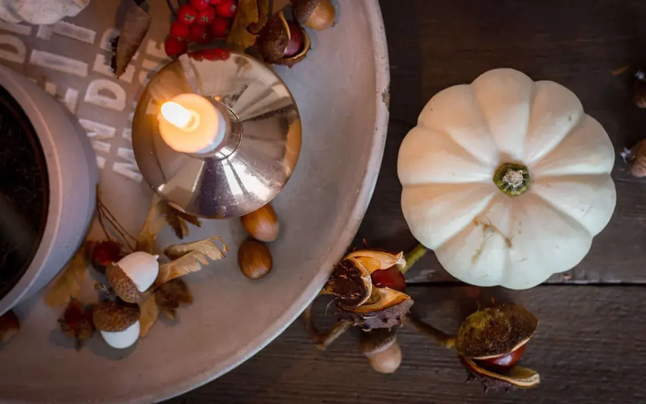 Gemütliche Herbstdeko-Ideen: Kerze, Kürbis, Eicheln und Kastanien auf einem Tablett.