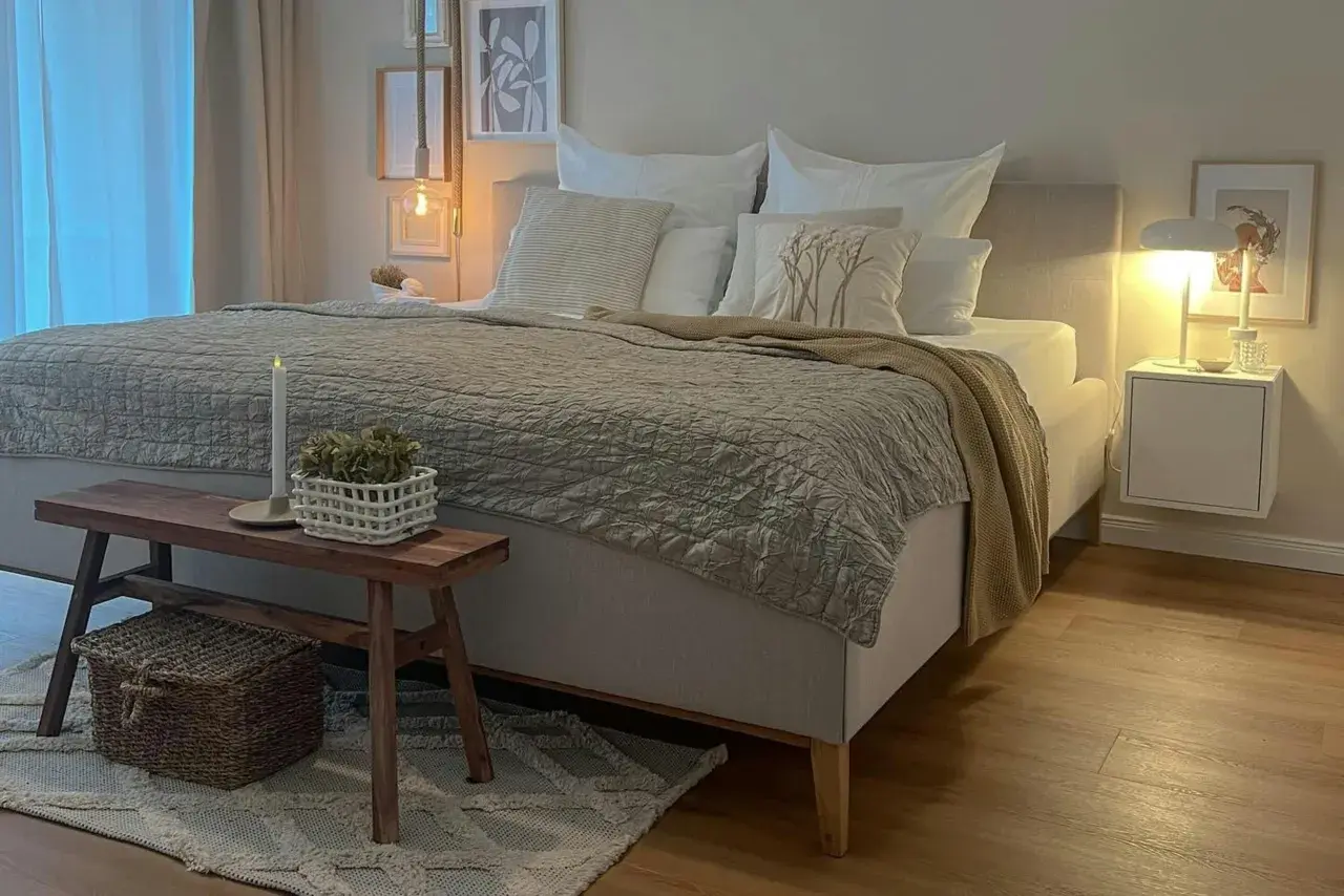 Gemütliches Schlafzimmer in Beige: Bett mit Steppdecke, Kissen und Holzbank. Tolle schlafzimmer beige ideen für eine entspannte Atmosphäre.