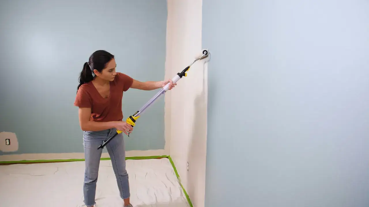 Frau streicht Wand mit Farbroller. Die Frage, wie lange braucht Wandfarbe zum trocknen, beschäftigt viele Heimwerker.