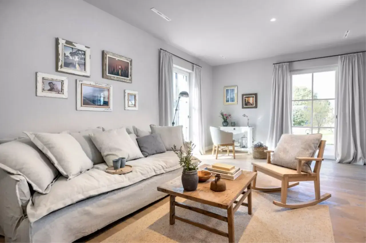 Gem&uuml;tliches Wohnzimmer mit grauem Sofa, Holztisch und Bildern. Hier sieht man, welche Farben passen zu grau: Beige, Wei&szlig; und nat&uuml;rliche Holzt&ouml;ne.