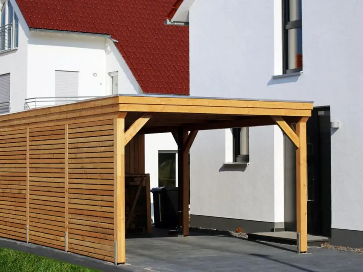 Moderner Holz-Carport neben einem wei&szlig;en Haus. Die Baugenehmigung f&uuml;r den Carport ist oft notwendig.
