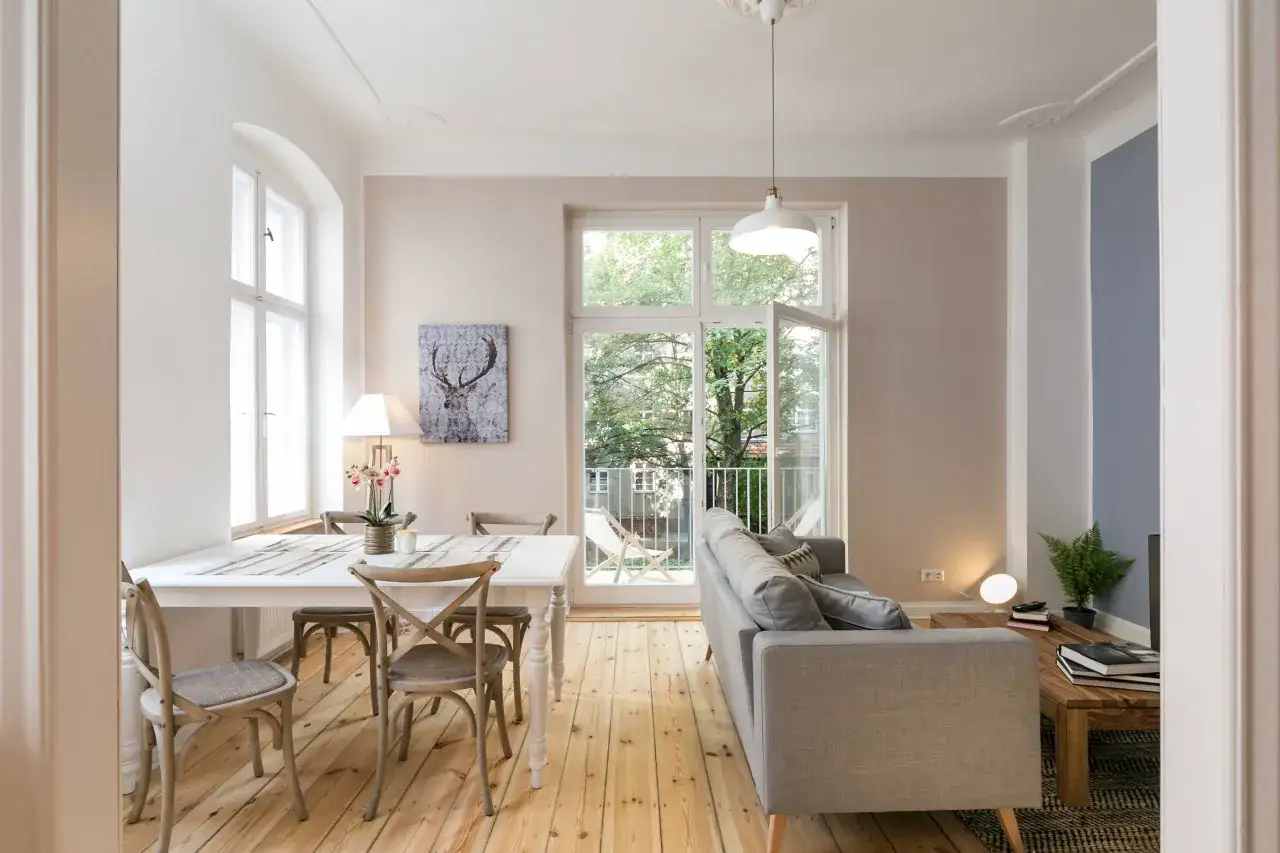 Helles, freundliches wohn esszimmer mit Esstisch, St&uuml;hlen, Sofa und gro&szlig;em Fenster mit Blick ins Gr&uuml;ne.
