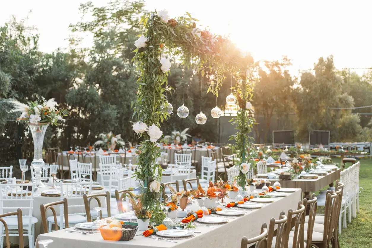 Festlich gedeckte Tische im Garten mit Blumenbögen und Lampions. Wunderschöne Dekoideen Hochzeit im Garten für eine romantische Feier unter freiem Himmel.