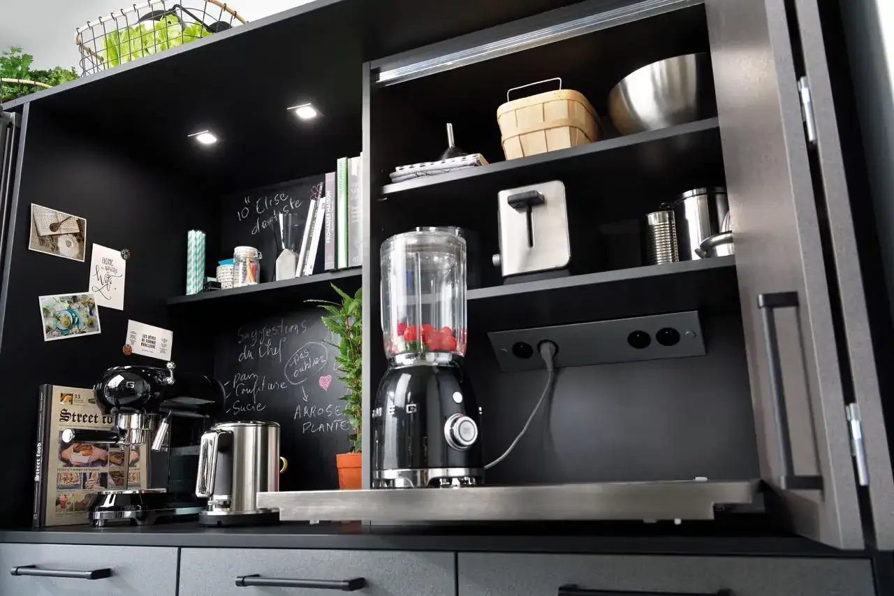 Schwarzer K&uuml;chenschrank mit integrierter Steckdose, Mixer, Kaffeemaschine und Toaster.
