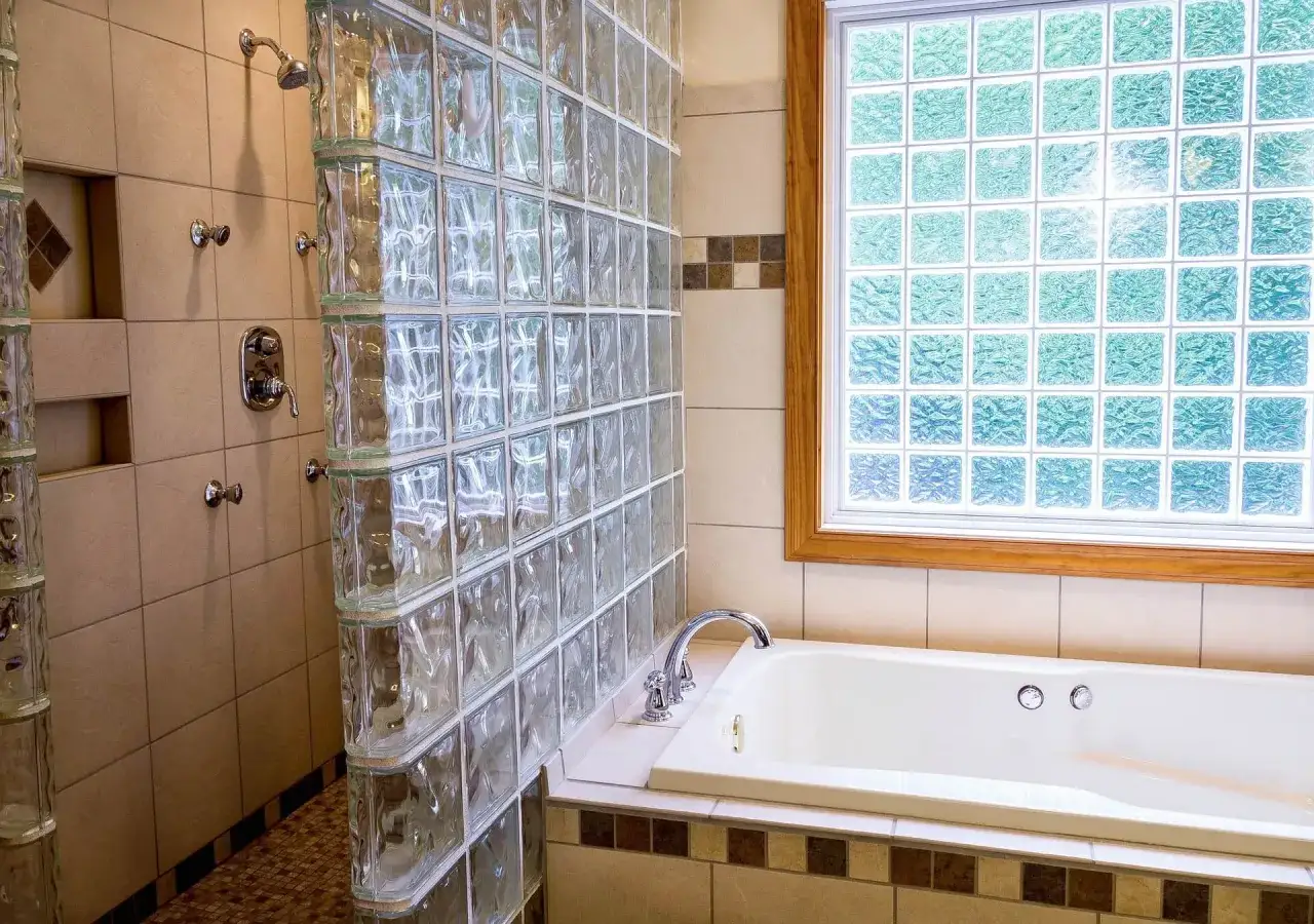 Moderne Dusche mit Glasbausteinen verlegen, die Licht hereinlassen. Daneben eine Badewanne und ein Fenster mit Glasbausteinen.