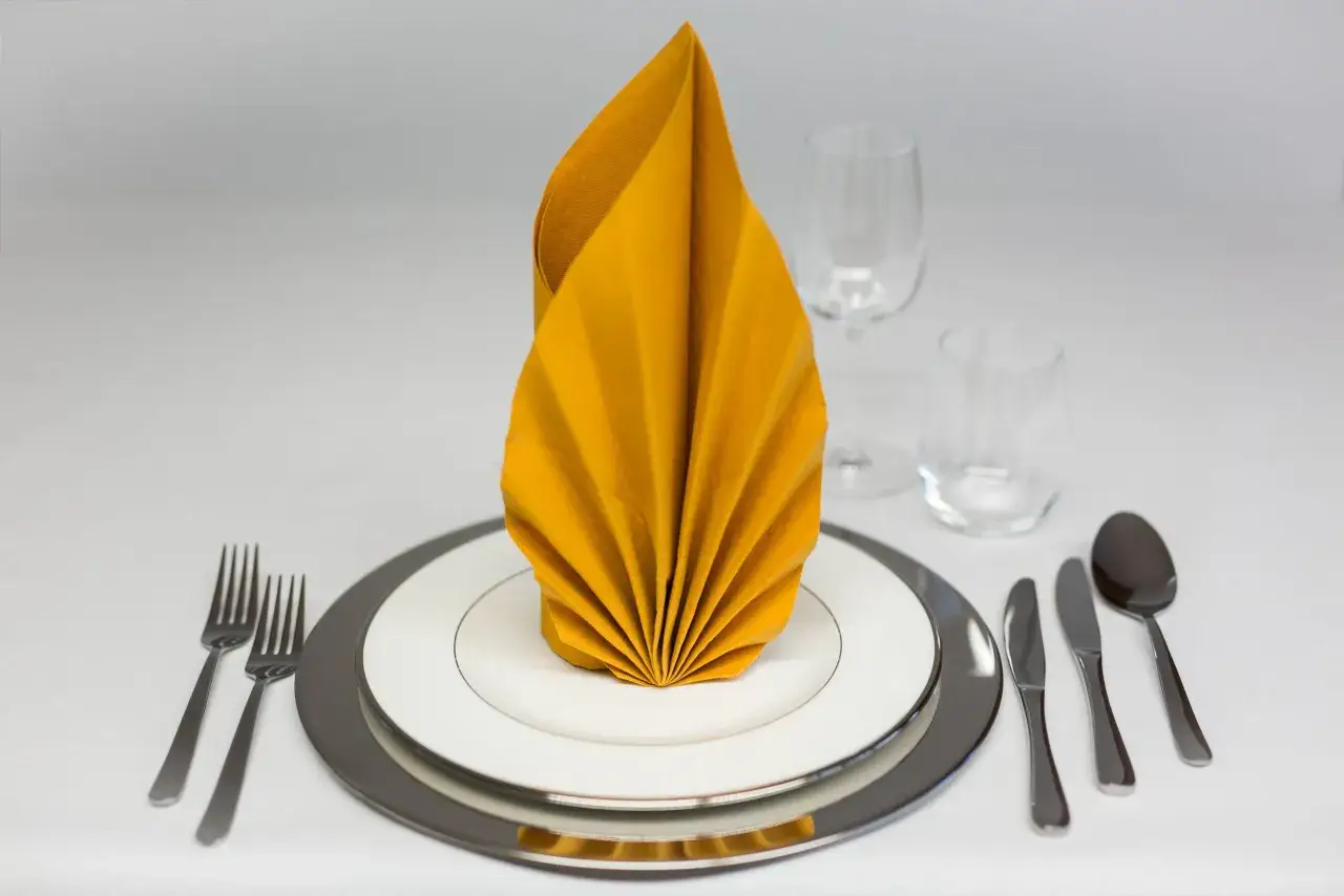 Elegante servietten falten liegend auf einem gedeckten Tisch mit Geschirr und Gläsern.
