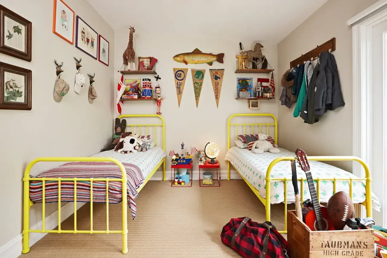 Zwei gelbe Betten in einem Kinderzimmer mit Spielzeug und Dekorationen. Tolle geschwisterzimmer ideen für Abenteuer!