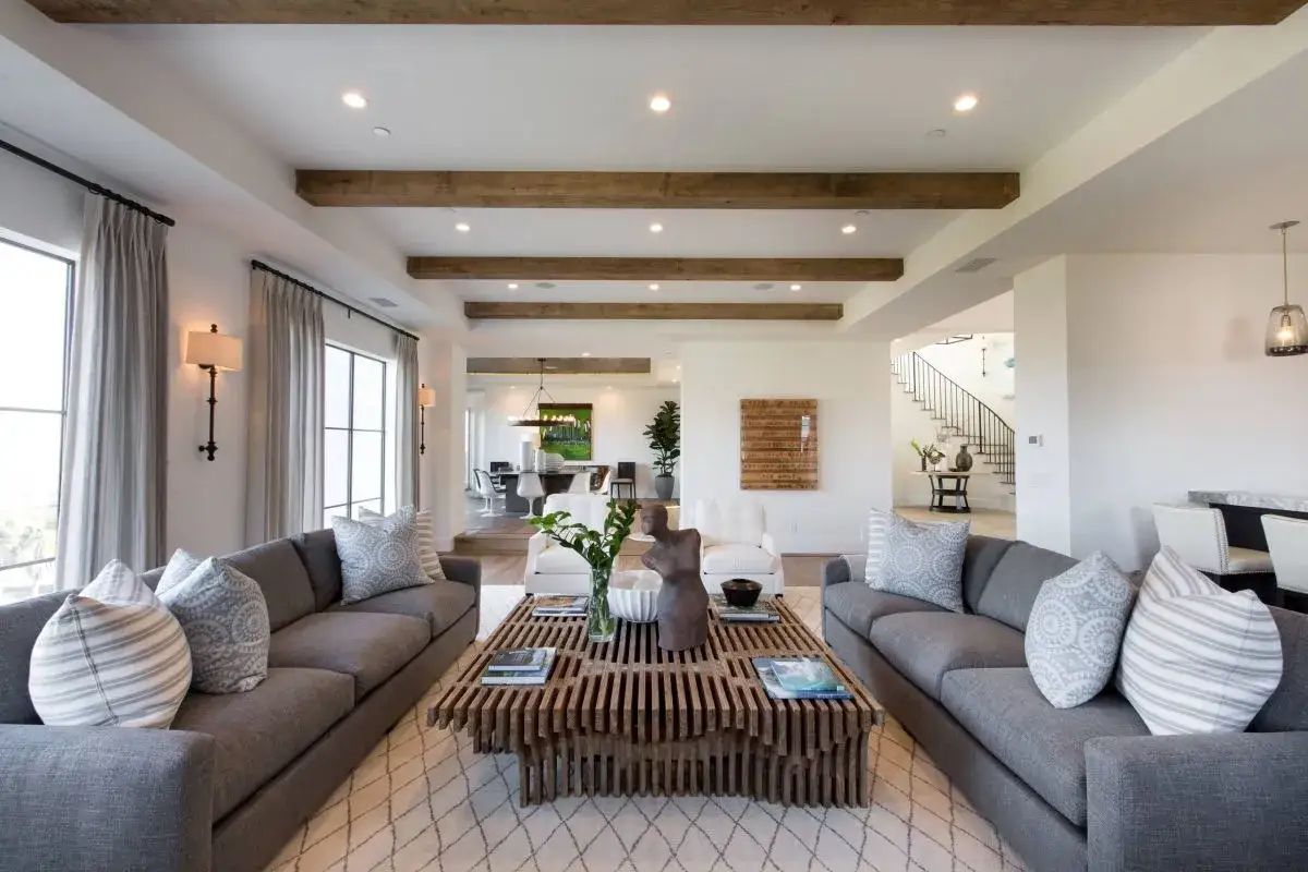 Modernes Wohnzimmer mit zwei grauen Sofas, einem Holztisch und Akzenten, die zeigen, wie gut passt grau und braun zusammen.
