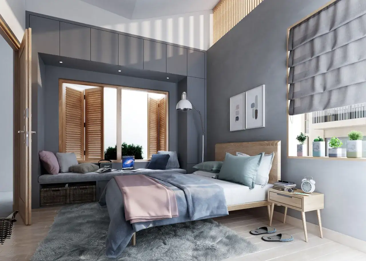 Gem&uuml;tliches Schlafzimmer mit einem Bett unter Fenster, das von Jalousien beschattet wird. Ein Laptop und Kissen laden zum Verweilen ein.