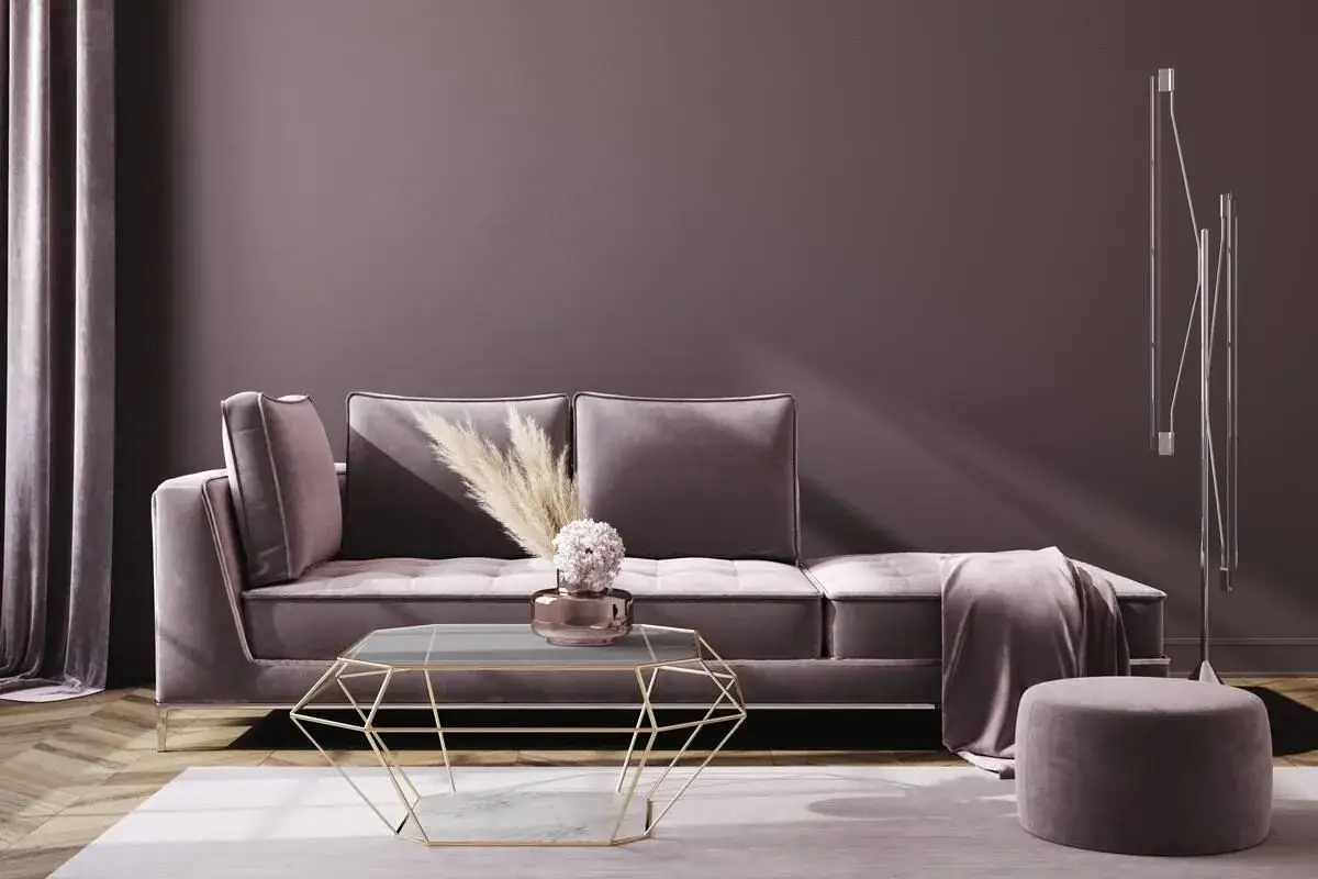 Ein gem&uuml;tliches Sofa in zarter mauve Farbe, daneben ein Pouf und ein moderner Couchtisch.