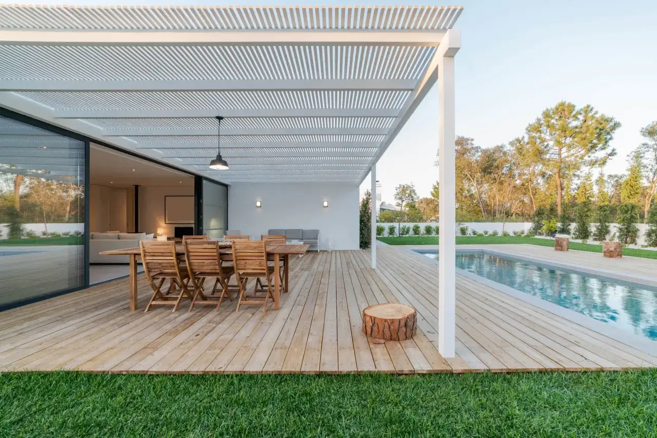 Ein modernes Terrassendach, das man gut selber bauen kann, &uuml;berspannt eine Holzterrasse mit Essbereich und Pool.