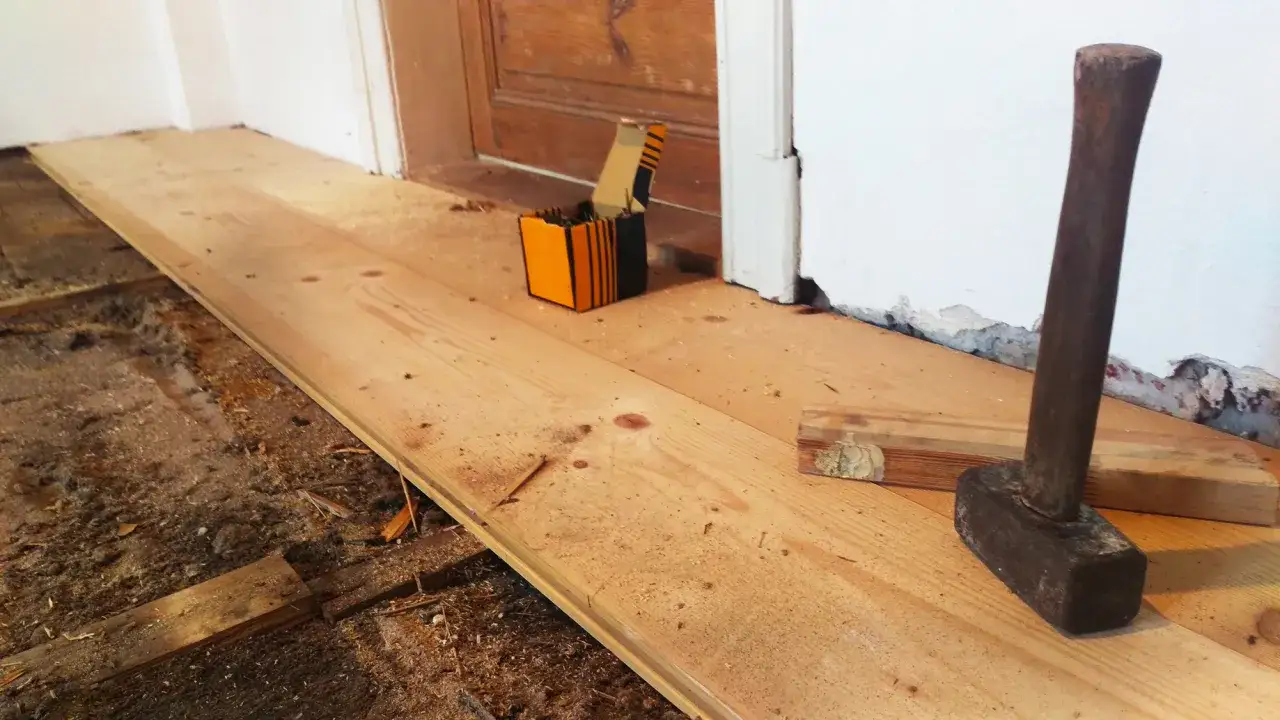 Neuer Dielenboden verlegen: Holzbretter liegen bereit, ein Hammer und N&auml;gel warten auf ihren Einsatz.