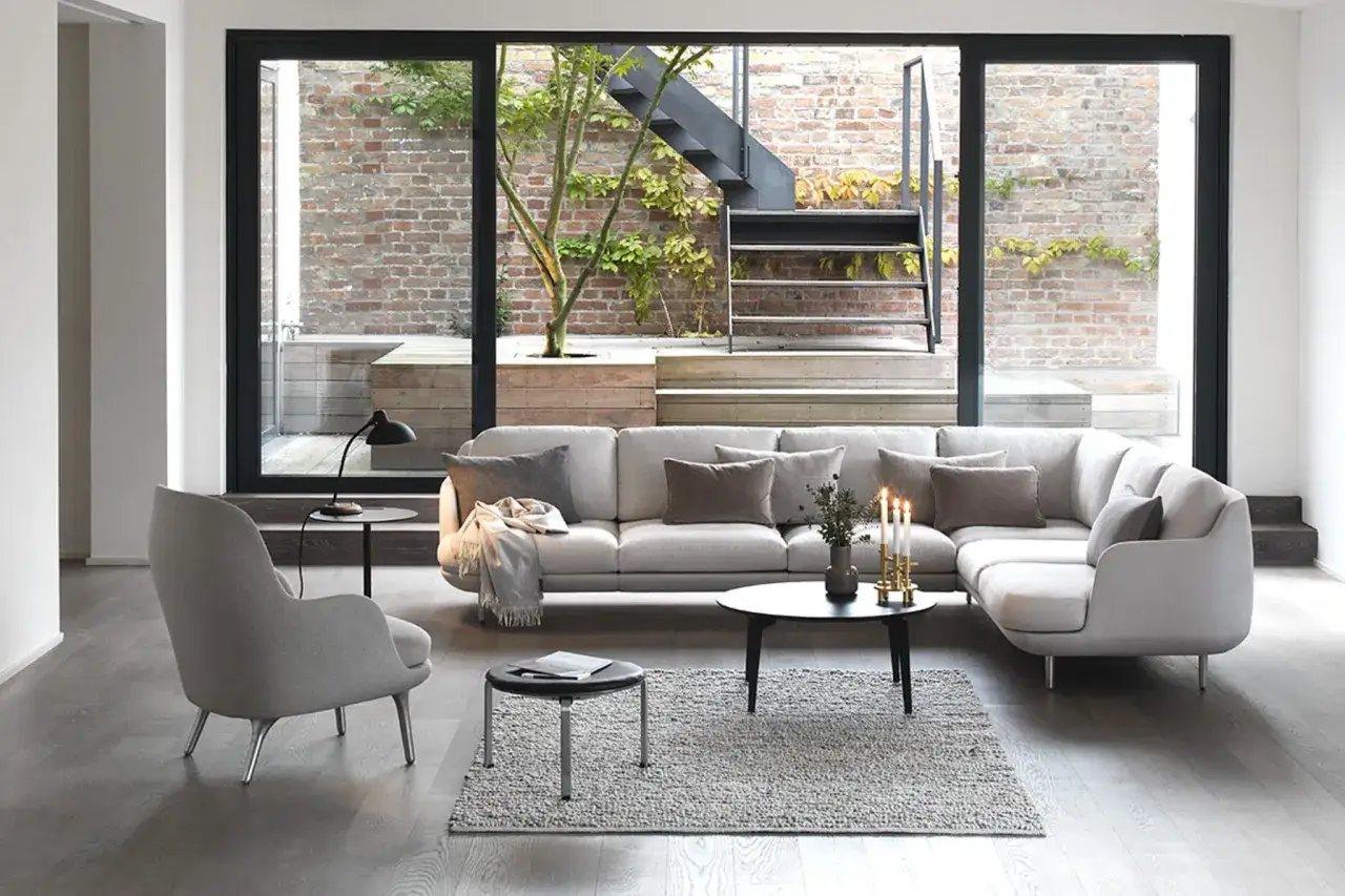 Moderne Anordnung Sofa Wohnzimmer mit bequemen Sesseln und Couchtisch. Ein Blick in den Garten mit Treppe und Ziegelwand.