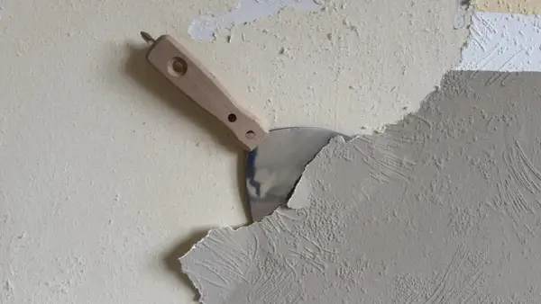Spachtel schält Tapete ab. Die Arbeit, Tapete entfernen, ist im Gange.