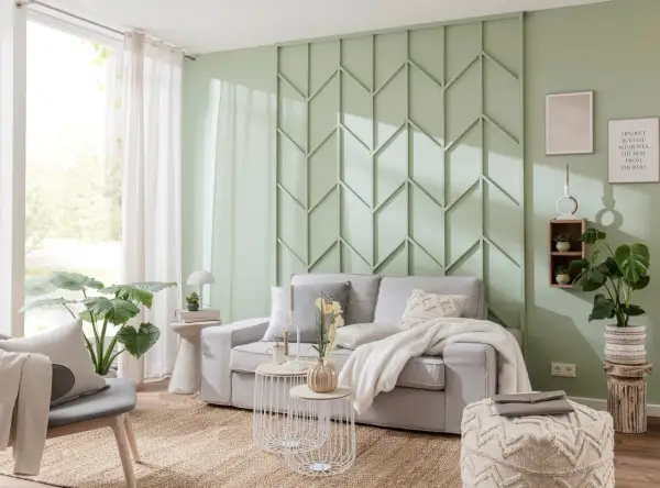 Moderne Wandgestaltung im Wohnzimmer hinter der Couch mit geometrischen Mustern in Mintgrün. Gemütliche Couch mit Kissen und Decke.