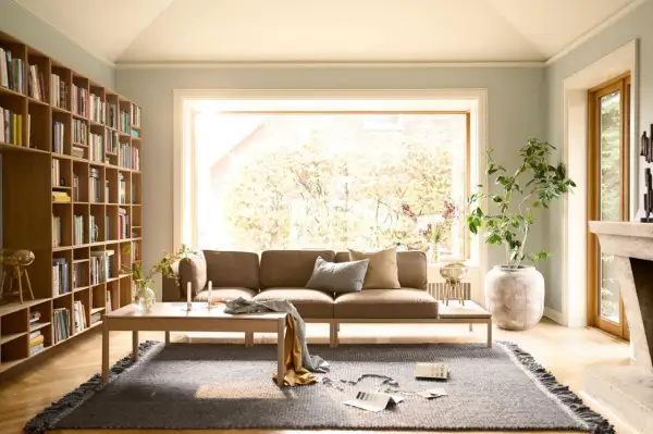 Gemütliche Anordnung Sofa Wohnzimmer mit Bücherregal, Kamin und großem Fenster.