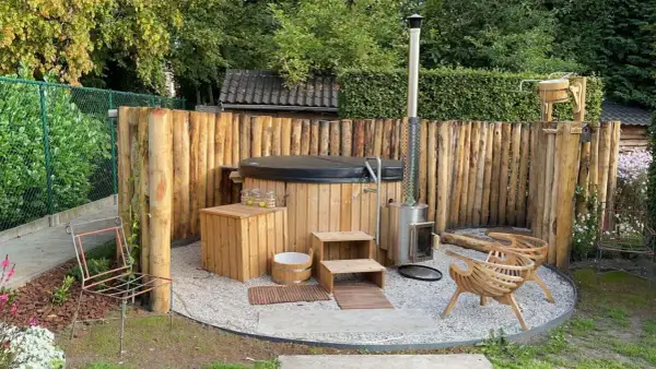 Natürliche Whirlpool Garten Ideen: Ein Holz-Whirlpool mit Holzverkleidung und Ofen, umgeben von rustikalen Holzstämmen.