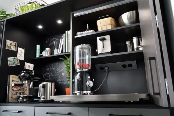 Schwarzer Küchenschrank mit integrierter Steckdose, Mixer, Kaffeemaschine und Toaster.