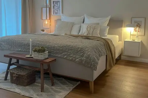Gemütliches Schlafzimmer in Beige: Bett mit Steppdecke, Kissen und Holzbank. Tolle schlafzimmer beige ideen für eine entspannte Atmosphäre.