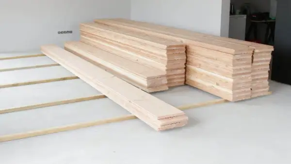 Holzdielen liegen bereit, um den **Boden auszugleichen**. Mehrere Stapel warten auf ihren Einsatz.