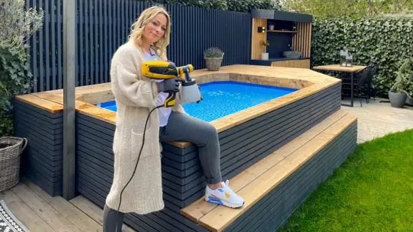 Frau mit Sprühgerät verkleidet aufstellpool mit Holz.